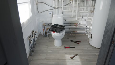 Tracking slowmo shot of various plumbing tools and toolbox lying on floor and toilet lid in bathroom with no people in it