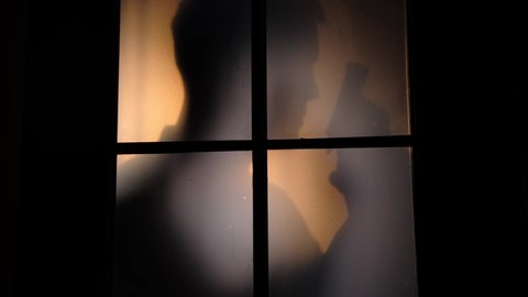 Silhouette of a man with a revolver outside the door
