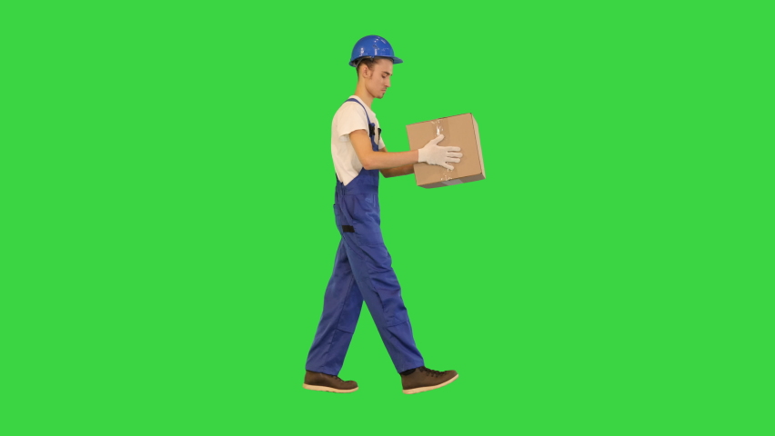 Man worker holding a box and walking on a Green Screen, Chroma Key.