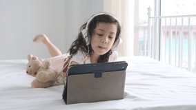Little asian girl learning online with tablet on bed.Cute child education and technology concept.