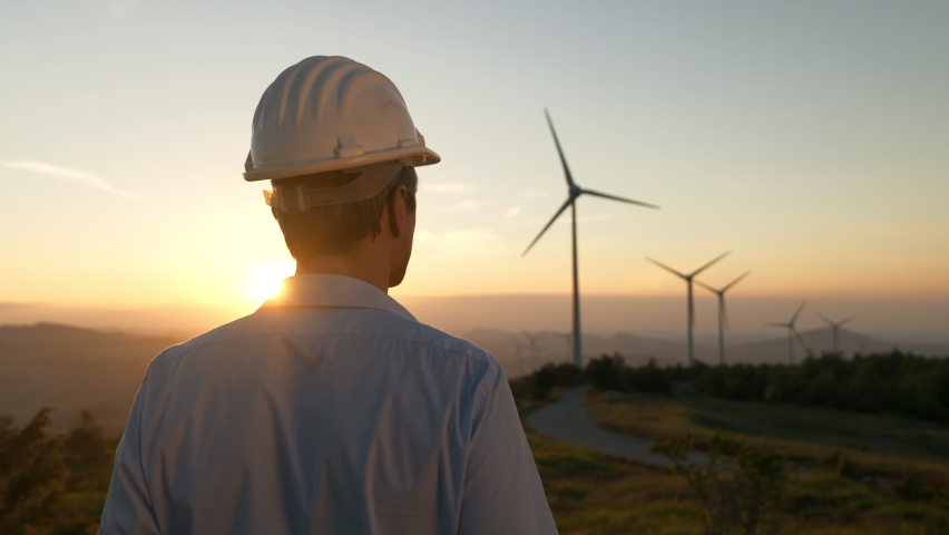 Cinematic shot of young engineer putting security helmet on satisfied with his job on background of wind mills with at sunset.Concept: renewable energy, technology, electricity, service, green, future Royalty-Free Stock Footage #1074980783