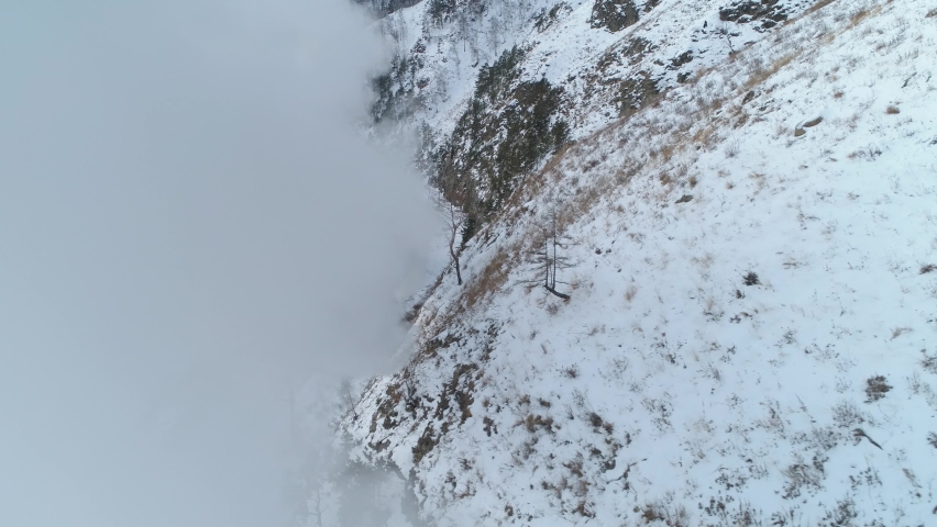 Flight sideways through white steam clouds incredible old steam locomotive historic steel train ride on railroad to tunnel Winter snowy Russia Siberia Circum-Baikal Transsib railway. Impressive travel