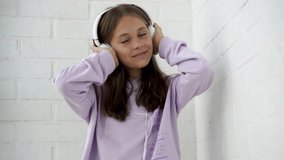 4k video. A little cute girl child listens to music with headphones and dances
