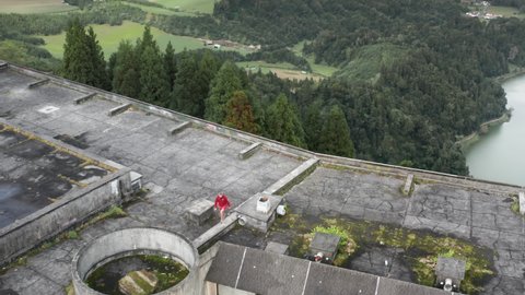 SAO MIGEL ISLAND, AZORES, PORTUGAL-14 MAY, 2021: Drone shot of young man walking on roof of Monte Palace hotel ruins, Cerrado das Freiras, Sao Miguel island, Azores ,Portugal, 4k footage