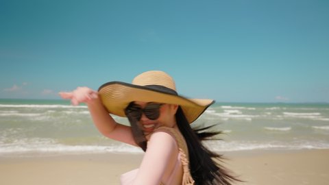 Asian Woman holding boyfriend hand and running on tropical beach to the sea on a holiday. An excited woman run and pulls her man hand to the beach on a summer day. Follow me. Slow motion shot