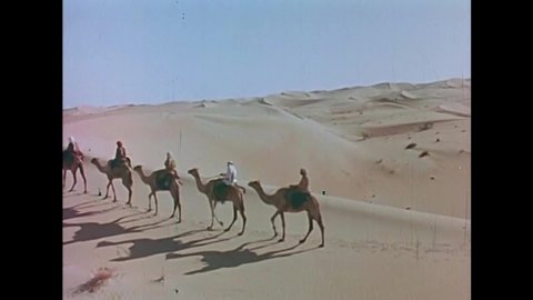 CIRCA 1973 - Bedouins ride camels across the sand on their pilgrimage to mecca in Saudi Arabia.