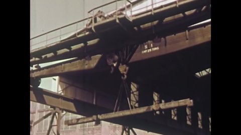 CIRCA 1960 - Steel beams are transported to a construction site, and workers put them into place.
