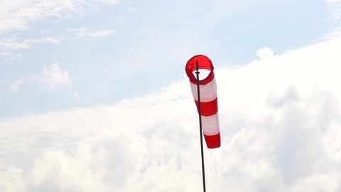 Airport or seaport windsock. Red white striped wind vane with blue sky.