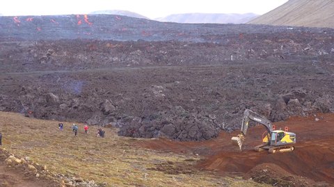 ICELAND - CIRCA 2020s - Construction equipment tries in vain to make dam or barrier to block the lava flow at the Fagradalsfjall volcano.