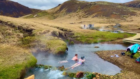 ICELAND - CIRCA 2020s - People bathe and soak in the hot springs and rivers of the Hveragerdi geothermal region along the mid Atlantic ridge.