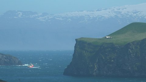 ICELAND - CIRCA 2020s - An Icelandic fishing boat battles difficult waves along a remote coast of the Westman Islands, Iceland.