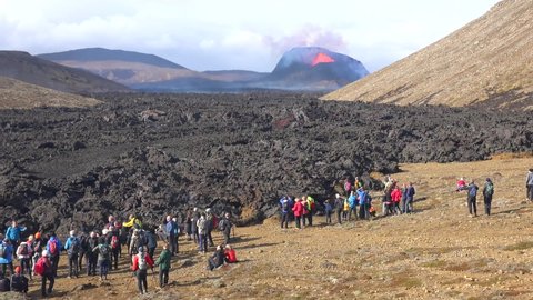 ICELAND - CIRCA 2020s - Tourists watch the eruption of the Fagradalsfjall volcano from the leading edge of the lava flow in Iceland.