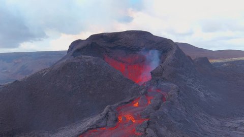 ICELAND - CIRCA 2020s - Slow tilt down of lava flowing from the crater at the Fagradalsfjall volcano volcanic explosive eruption in Iceland.