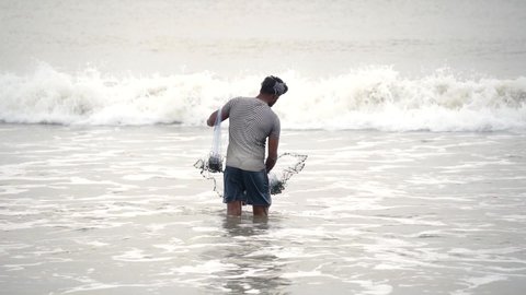 Kovalam Chennai, Tamil Nadu, India - June 28 2021: Man fishing in the sea with his fishing net in slow motion after covid lockdown restrictions ease 