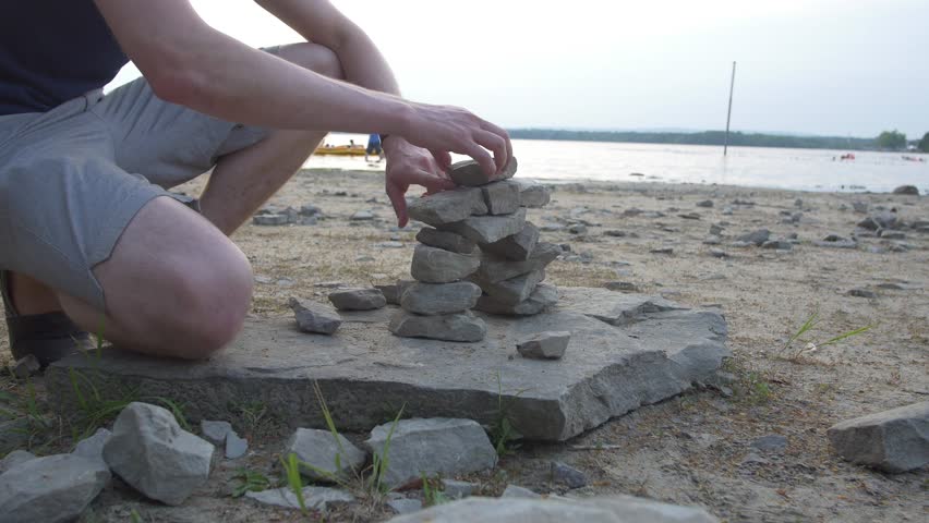 Man builds Inukshuks on beach 