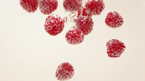 Raspberry splash falling into water, white background, aqua silver bubble drops