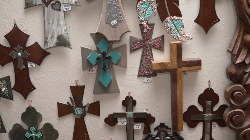 This tilt video shows a large collection and retail display of souvenir western style crosses and religious sculptures for sale.