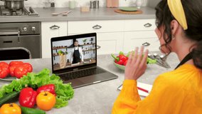 Woman housewife in home kitchen study online remote video call webcam laptop greets listen teacher. Man professional chef in computer screen tells removes food vegetables ingredients from paper bag