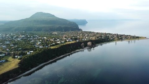 Aerial View, wide shot of a Lakeshore view in Lake Taupo, in the early springtime in New Zealand on a calm day, truck right.