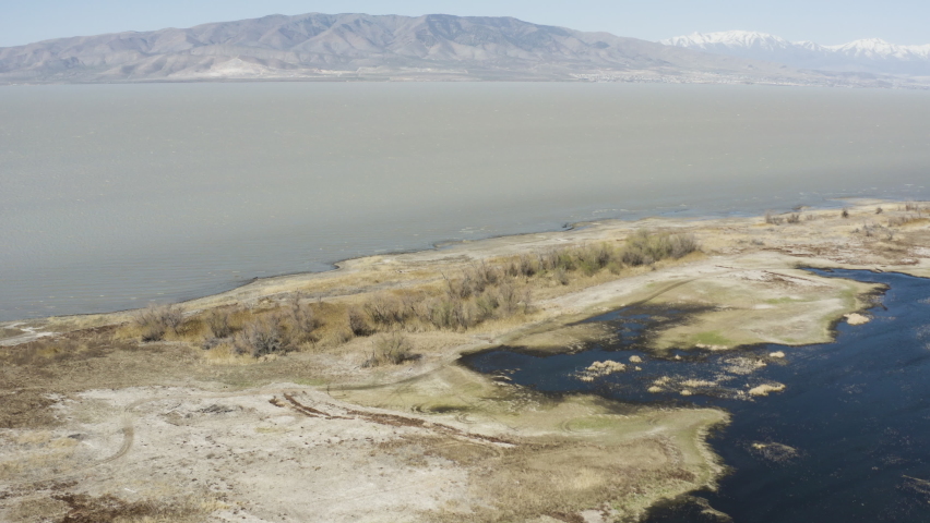Vast wetland expanse with sweeping views toward mountain range in Utah, USA. Drone aerial shot.