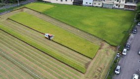 Aerial drone footage Cultivated rice paddy field, farmer harvesting the crops with multifunctional paddy harvesting machine rice harvester tractor at Doliu Yunlin Taiwan.