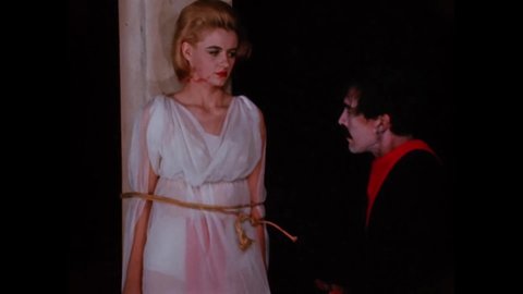 CIRCA 1966 - In this horror film, the leader of a Satanist cult slaps a woman tied to a pole as a human sacrifice.