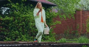 Gardening people. Gardener young woman with watering can speaking on phone smiling while planting outdoor