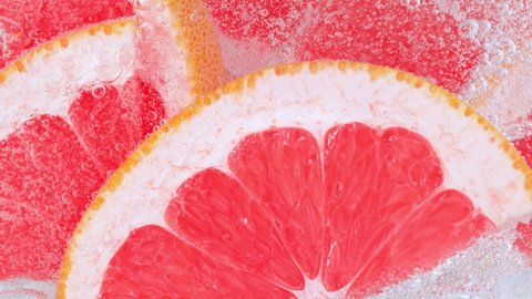 Super Slow Motion Shot of Fizzing Water with Grapefruit Slices and Ice Cubes in Glass at 1000 fps.