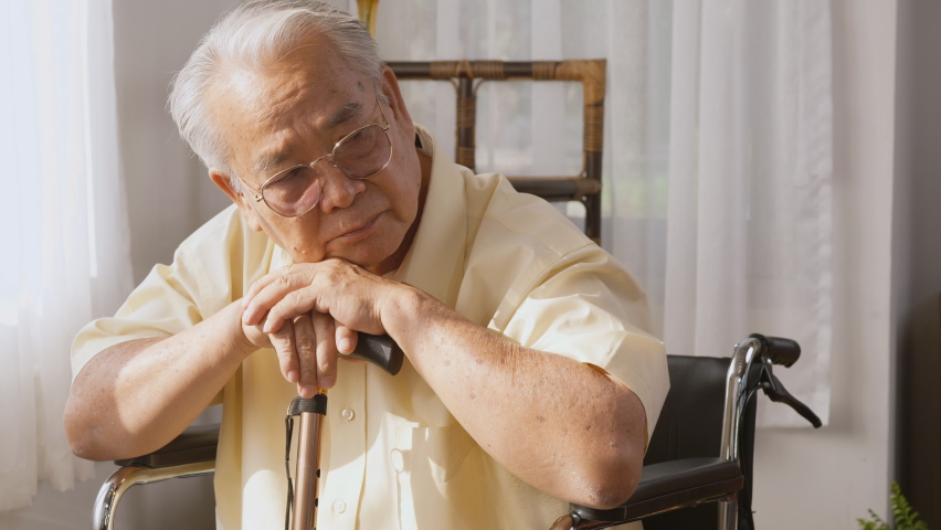Pensive disabled elderly patient sit on wheelchair alone, Sad and depressed Asian senior old man head down feel lonely and bored waiting for take care white room dementia and Alzheimer, slow motion | Shutterstock HD Video #1075017668