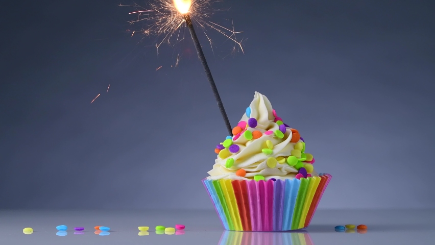 Birthday cupcake. Rainbow Cup Liners. Sparklers or fireworks Burning in a cake. Happy Birthday Gay, lesbian. LGBT pride. Tasty baking cupcakes or muffin with white cream icing and colored sprinkles. Royalty-Free Stock Footage #1075023173