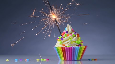 Birthday cupcake. Rainbow Cup Liners. Sparklers or fireworks Burning in a cake. Happy Birthday Gay, lesbian. LGBT pride. Tasty baking cupcakes or muffin with white cream icing and colored sprinkles.