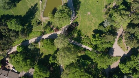 Drone top-down view of a public park with a pond and some pedestrian roads.