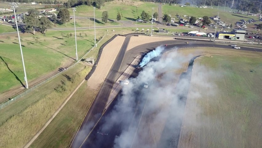 Cars Racing On Asphalt Race Track With Lots Of Smoke From Burning Tires - aerial shot
