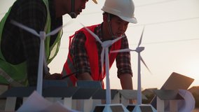 Asian engineer, foreman or leader discussion about home solar cell farm and wind turbine model in construction site project and High voltage power line pylon at sunset. Teamwork, Leadership concept - Powered by Shutterstock - Get 15% off with code: PIKWIZARD15