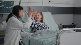 Pediatric woman doctor interacting with sick patient giving high five during clinical consultation in hospital ward. Child lying in bed wearing oxygen nasal tube waiting for medication treatment - Powered by Shutterstock - Get 15% off with code: PIKWIZARD15