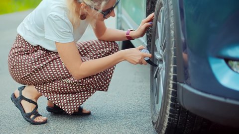 Woman Check Car Tire Pressure. Vehicle Trouble On Road On Vacation Trip. Female Trying Fix Car Tire. Rent Transportation. Problem With Car On Countryside Road. Automobile Repair Inflating Tire Check
