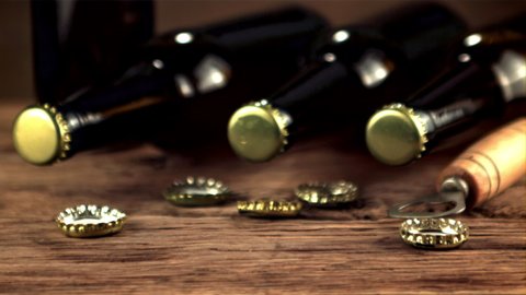 Super slow motion lids from beer bottles fall on the table. On a wooden background.Filmed on a high-speed camera at 1000 fps.