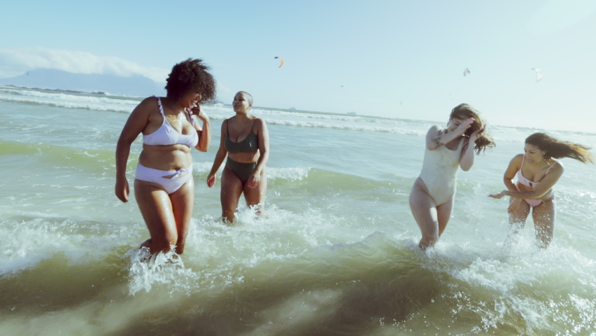 Multi-ethnic women in bikinis enjoying themselves at the beach. Group of different size women in swimwear coming out of the sea water together.
 Royalty-Free Stock Footage #1075040618