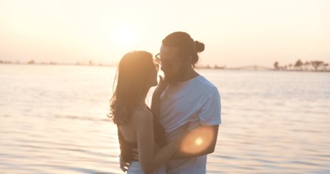 Romantic young couple is dancing on seaside, beach in golden hour sunset. Happy woman and man's relationship. Happiness, relaxing concept.