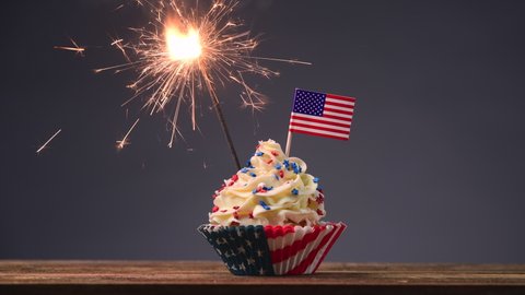 Cupcake American Flag. Sparklers or fireworks lights burning in a cake. 4th of July, Independence, Presidents Day. Tasty cupcakes with white cream icing and colored stars sprinkles. Sweet dessert.