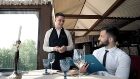 In The Restaurant, The Waiter Takes The Order Of A Stylish Man In An Elite Restaurant. customer service. A waiter who gives recommendations in a restaurant. The client becomes familiar with the menu - Powered by Shutterstock - Get 15% off with code: PIKWIZARD15