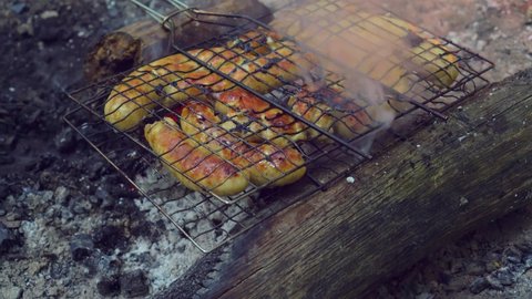 Sausages are grilled on the barbecue grill in the open air. Grilled food, grilled and smoked on charcoal grills. a bonfire is burning. delicious sausages on the grill rack. Picnic food.