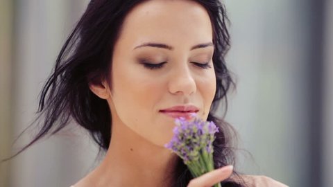 Portrait of a pretty young woman sniffing a bouquet of lavender. Beautiful woman inhales the fragrance of flowers. The girl face close up with a bouquet of lavender. 
