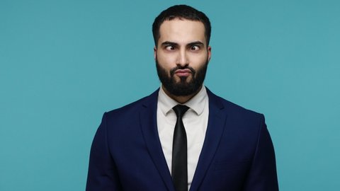 Funny bearded man in formal suit looking at camera with big eyes, making fish face grimace pout lips, smooching choking with idiotic duck expression. Indoor studio shot isolated on blue background.