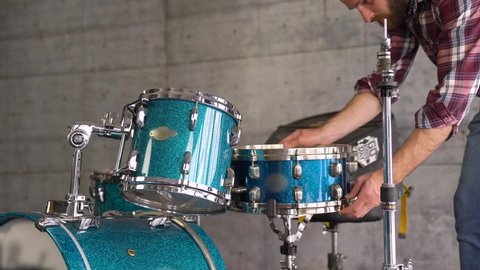 Bearded Casual Man is Setting Up A Drum Set  before Playing - Drum Lesson. 