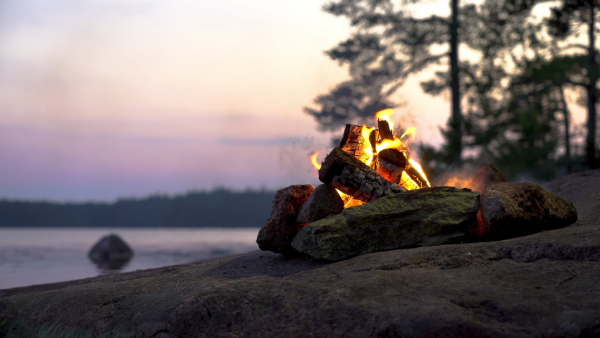 A bonfire burning in a forest on the shore of a lake at midnight on the Summer Solstice. Summer White Night on the eve of Midsummer Day in Finland. Sound of campfire and wildlife, birdsong Royalty-Free Stock Footage #1075071851