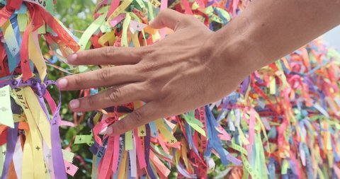 Closeup of colorful ribbons in Bahia, Brazil. Man hand making an request with Brazilian ribbons. Faith. 4K.