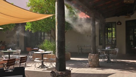 June 29, 2021: Mercado San Agustin, Tucson, Arizona. Artificial mist created by an outdoor cooling system. People on restaurant patio.