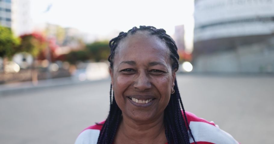African senior woman smiling on camera with city in the  background