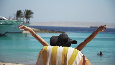 Happy relaxing woman on the exotic beach enjoying the view of the turquoise sea and yacht